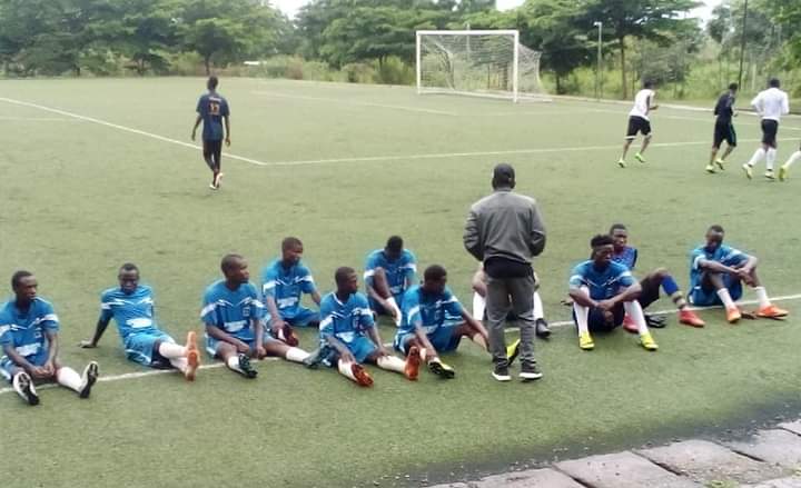 Football team sitting on pitch with coach
